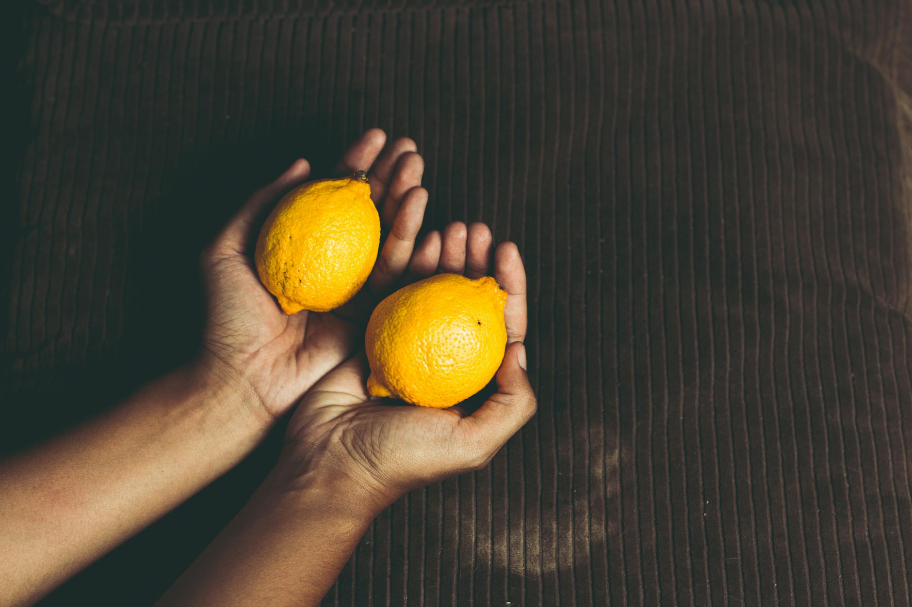 Two fresh lemons held gently in cupped hands, symbolizing the care and gentleness needed for comfortable pleasure