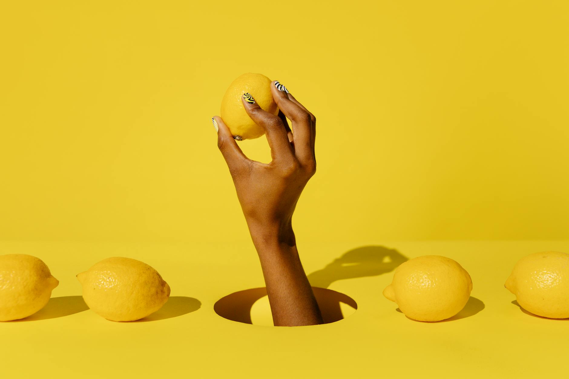 Hand holding a fresh lemon against a vivid yellow background, symbolizing the bright, renewed pleasure possible after menopause